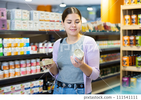Young happy woman choosing canned pet food in pet shop 111541111