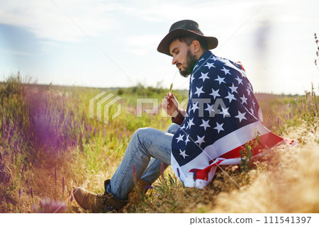 4th of July. American Flag.Patriotic holiday. Traveler with the flag of America. Beautiful sunset light. American style. 111541397