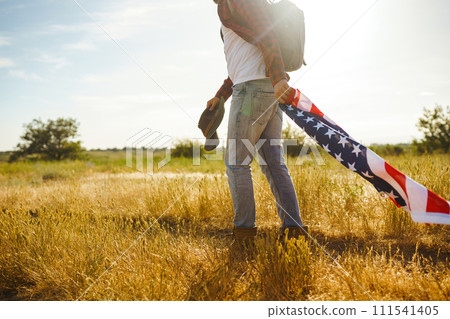 4th of July. American Flag.Patriotic holiday. Traveler with the flag of America. Beautiful sunset light. American style. 111541405
