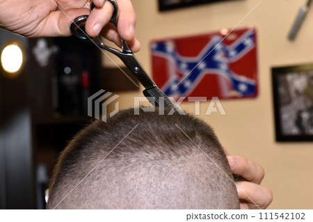 A hairdresser uses scissors to cut hair from a client's head. A hairdresser uses scissors to cut hair from a client's head. 111542102