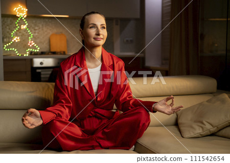 Serene Woman Practicing Meditation in Lotus Position at Home During The Evening 111542654