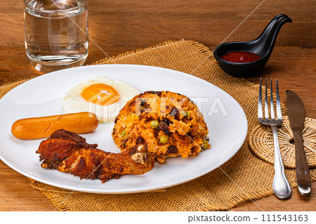 American fried rice with fried drumstick, fried egg and sausage in white ceramic plate. 111543163