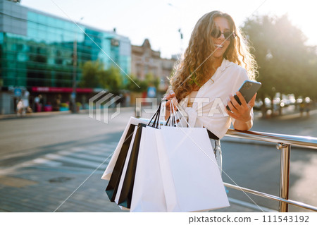 Beautiful woman with shopping bags makes selfie. Young woman walking shopping. Lifestyle concept. Beautiful woman with shopping bags makes selfie. Young woman walking shopping. Lifestyle concept. 111543192