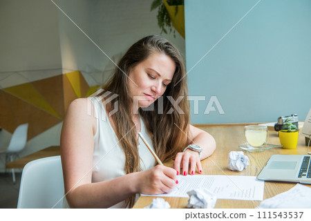 Focused young businesswoman or student taking notes while working on laptop. Female having online meeting or educational course in cafe, coworking. Remote work, social networks, blogging. Freelancer. 111543537