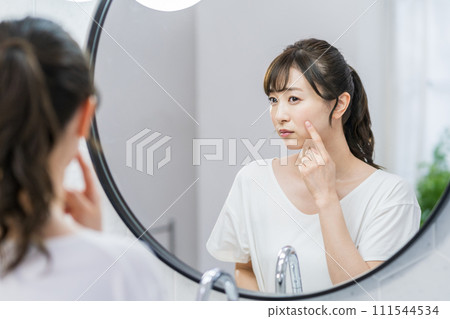 A woman checking her skin condition in front of the mirror. A woman checking her skin condition in front of the mirror. 111544534
