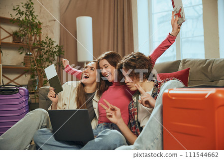 Happy young people sitting at home with tickets, making online hotel reservation, preparing for upcoming trip. Travel companies 111544662