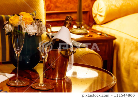 Champagne bottle in an ice bucket with two champagne glasses Champagne bottle in an ice bucket with two champagne glasses 111544900