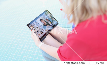 A woman by the pool holds a tablet on her lap, blurry A woman by the pool holds a tablet on her lap, blurry 111545781