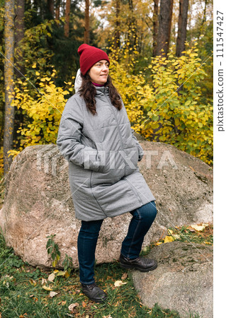 Portrait of a woman in a red knitted hat and a gray fashionable jacket Portrait of a woman in a red knitted hat and a gray fashionable jacket 111547427