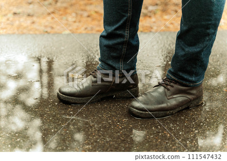 female legs in jeans and black boots standing on wet asphalt in rain female legs in jeans and black boots standing on wet asphalt in rain 111547432