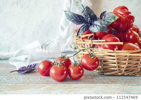 Ripe red cherry tomatoes in a wicker basket on a wooden background. 111547469