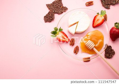 Brie cheese with strawberries, pecans nuts, crackers and honey on pink background. Flat lay. Copy space 111547547