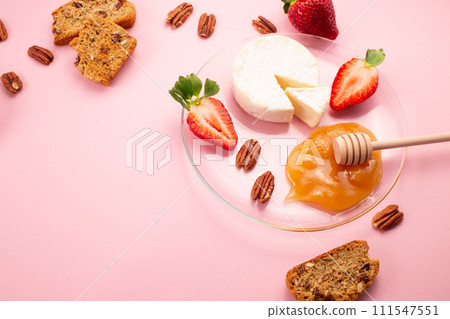 Brie cheese with strawberries, pecans nuts, crackers and honey on pink background. Flat lay. Copy space 111547551