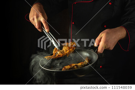 Preparing a fish dish in a restaurant kitchen. The cook fries fish in a frying pan. Black space for advertising Preparing a fish dish in a restaurant kitchen. The cook fries fish in a frying pan. Black space for advertising 111548039