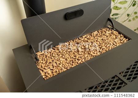 Image of a pellet stove with the hopper filled to the brim with ecological fuel, sustainable and renewable heat. 111548362
