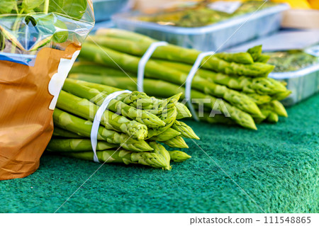 Bunch of green asparagus sitting on green carpet next to bag of broccoli Bunch of green asparagus sitting on green carpet next to bag of broccoli 111548865