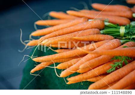 Pile of carrots sitting on top of green cloth covered table 111548890