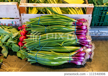 Pile of green onions and radishes sitting on top of table 111548906