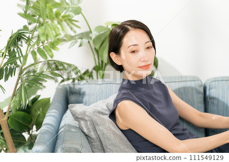 A woman in her 30s with short hair sitting on a sofa 111549129