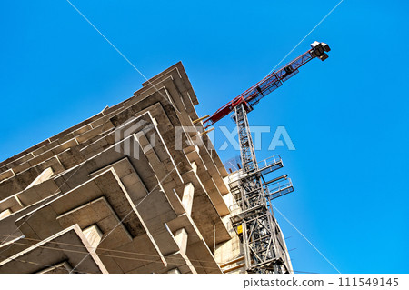 Crane on top of building with blue sky in the background. 111549145