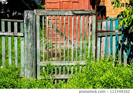 Green wooden gate in front of red door and window. Green wooden gate in front of red door and window. 111549162