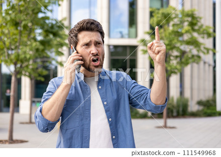 Surprised mature businessman communicating on smartphone outdoors. Casual corporate professional gesturing with urban office backdrop. Surprised mature businessman communicating on smartphone outdoors. Casual corporate professional gesturing with urban office backdrop. 111549968