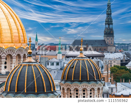 The Nativity of Christ Cathedral in Riga, Latvia. Byzantine-styled Orthodox cathedral, the largest in the Baltic region, with golden colored dome, polished gilded cupolas gleaming through the trees The Nativity of Christ Cathedral in Riga, Latvia. Byzantine-styled Orthodox cathedral, the largest in the Baltic region, with golden colored dome, polished gilded cupolas gleaming through the trees 111550362