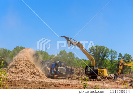 Using forestry mulcher, we loaded roots from trees to an industrial shredder machine that chopped Using forestry mulcher, we loaded roots from trees to an industrial shredder machine that chopped 111550934