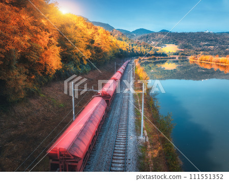 Aerial view of freight train moving near river in mountains 111551352