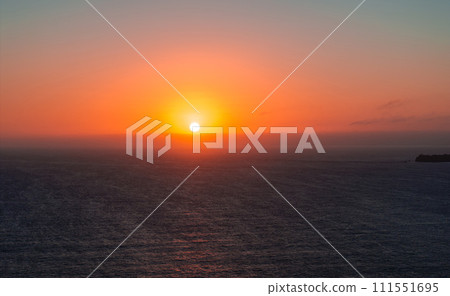 Bright sunset with large yellow sun under the Pacific ocean. Orange and golden sunset sky calmness tranquil relaxing sunlight summer mood. 111551695
