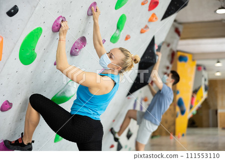 Female mountaineer protective mask climbing artificial rock wall without belay indoors 111553110