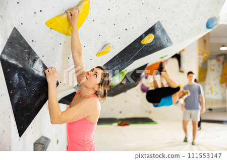 Female mountaineer climbing artificial rock wall without belay indoors Female mountaineer climbing artificial rock wall without belay indoors 111553147