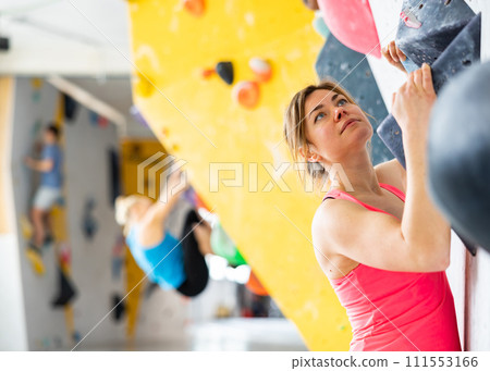 Female mountaineer climbing artificial rock wall without belay indoors 111553166