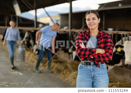 Positive young woman farmer in cowshed Positive young woman farmer in cowshed 111553244