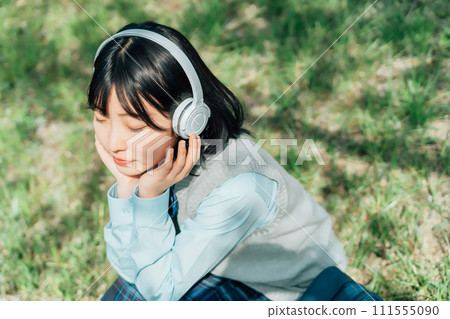 High school girl listening to music outdoors 111555090