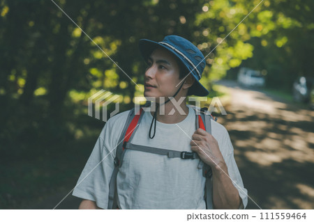 A man walking along a forest road with a backpack on his back 111559464