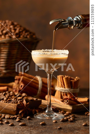Irish cream and coffee liqueur is poured from a bottle into a glass. 111559893