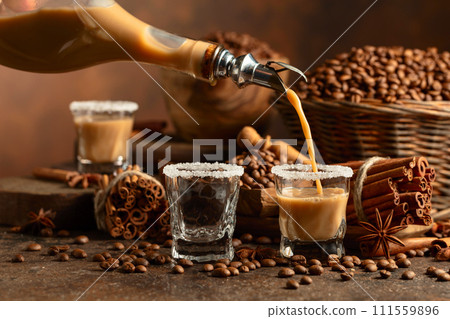 Irish cream and coffee liqueur is poured from a bottle into a glass. Irish cream and coffee liqueur is poured from a bottle into a glass. 111559896
