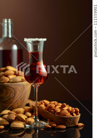 Italian liqueur Amaretto with almonds nuts on a brown background. 111559901