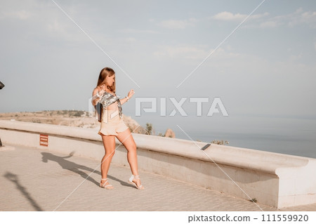 Woman summer dance. Silhouette of a happy woman who dances, spins and raises her hands to the sky. A playful young woman enjoys her happy moment dancing in the rays of the golden sun. 111559920