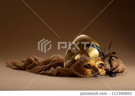 Golden Venetian carnival masks on a beige background. 111560663