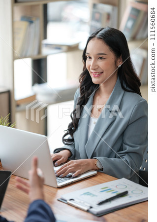 Two business workers smiling happy working sitting on desk at the office. Two business workers smiling happy working sitting on desk at the office. 111560684
