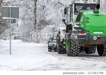 Tractor clears snow on road after heavy snowfall, road maintenance in winter season, harsh weather Tractor clears snow on road after heavy snowfall, road maintenance in winter season, harsh weather 111561796