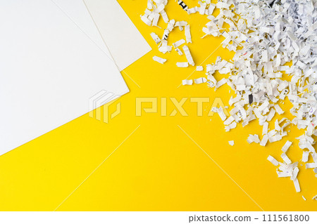 Shredded white paper on light yellow background 111561800