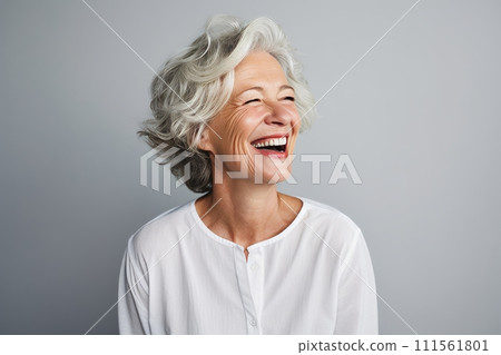 Cheerful senior woman laughing and looking at camera against grey background. 111561801