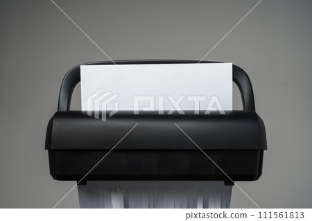 Black paper shredder cutting paper on gray background Black paper shredder cutting paper on gray background 111561813