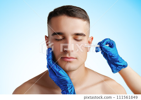Handsome young man face and beautician hands with syringe making cosmetic injection in face Handsome young man face and beautician hands with syringe making cosmetic injection in face 111561849