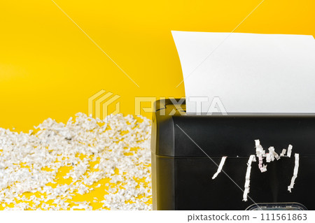Office paper shredder on yellow studio background 111561863