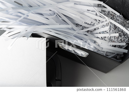 Black paper shredder cutting paper on gray background Black paper shredder cutting paper on gray background 111561868