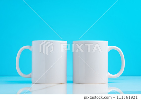 Two ceramic mugs on blue studio background 111561921